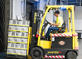 Man driving forklift with sachet packaging in warehouse